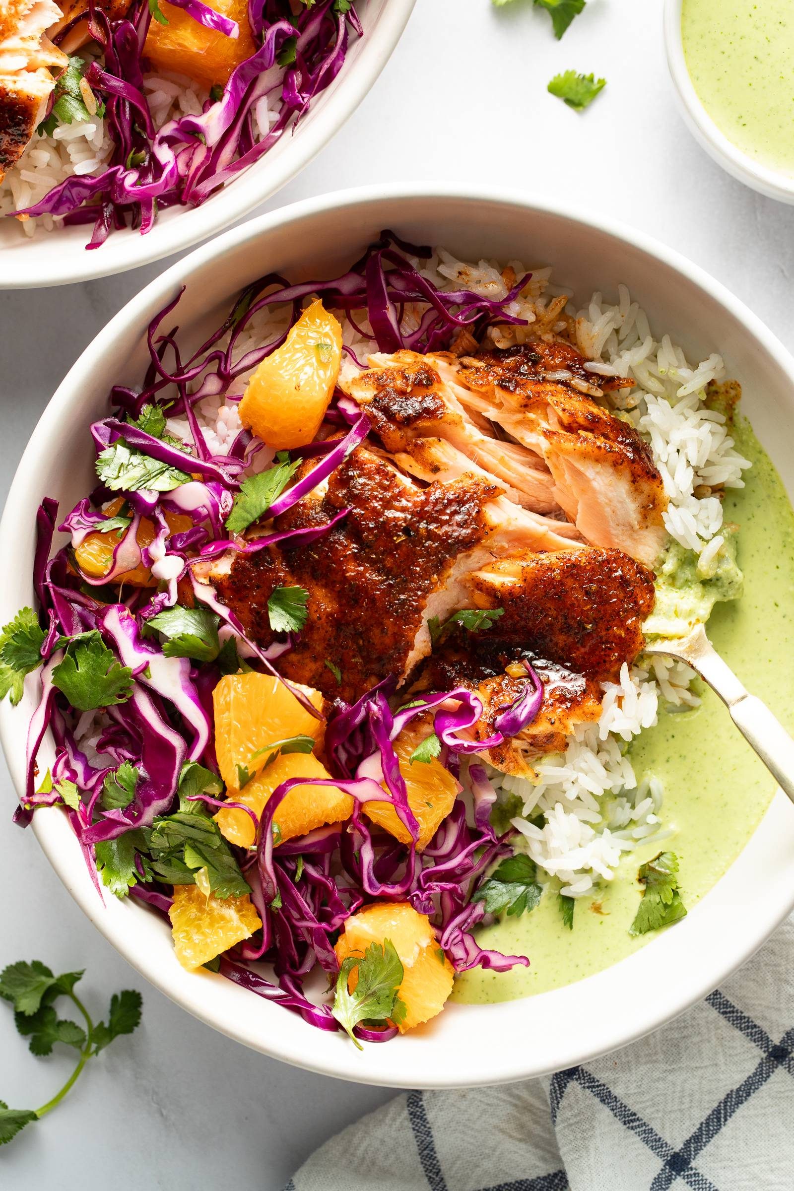 Chipotle salmon in a bowl with rice, slaw, and sauce.