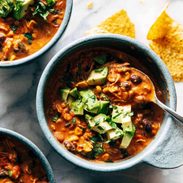 Queso chicken chili in a bowl with avocado on top.