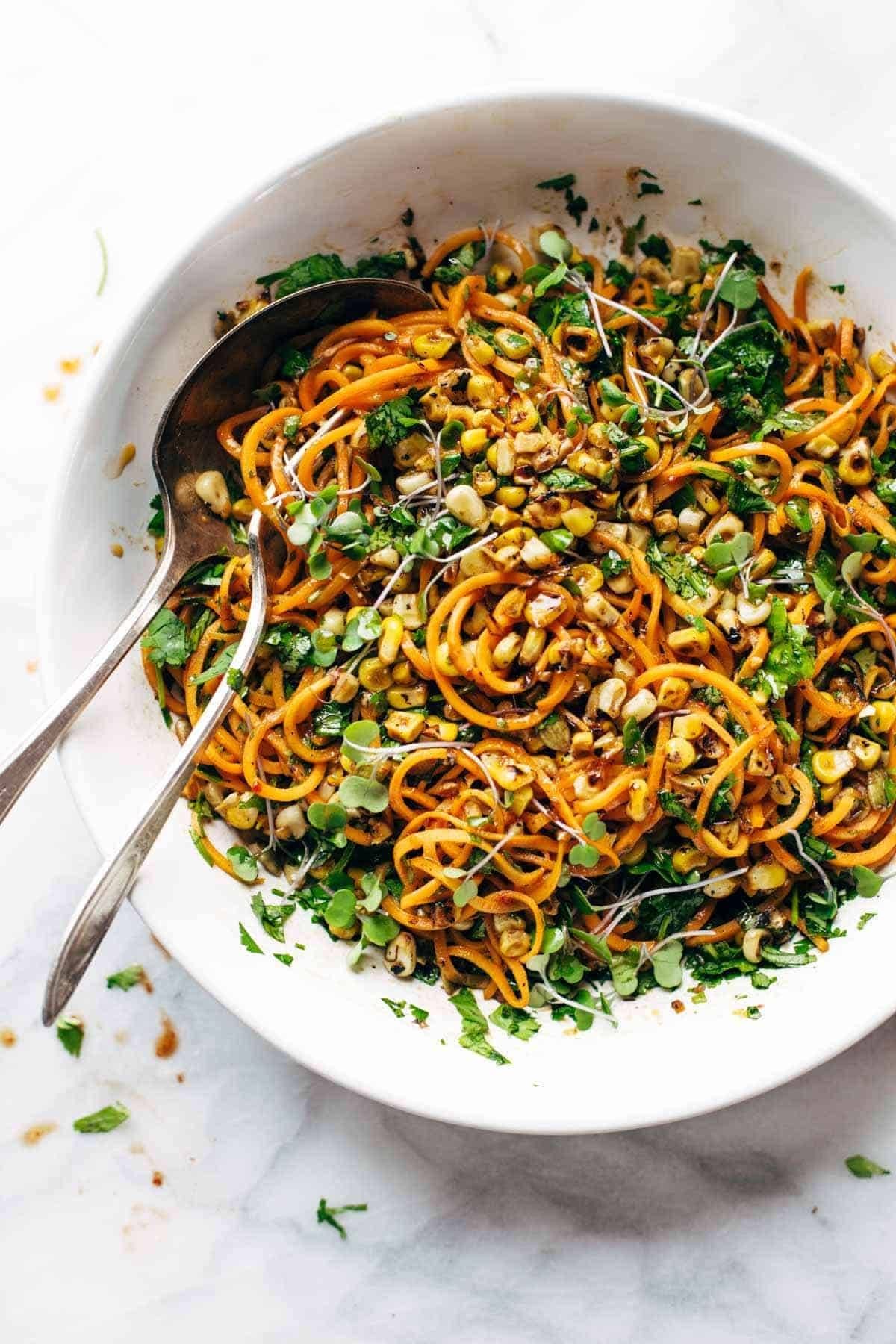 Sweet potato noodle salad in a bowl with two spoons.