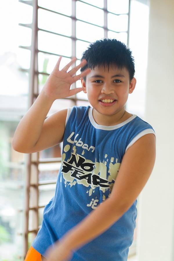 Young boy waving and smiling.
