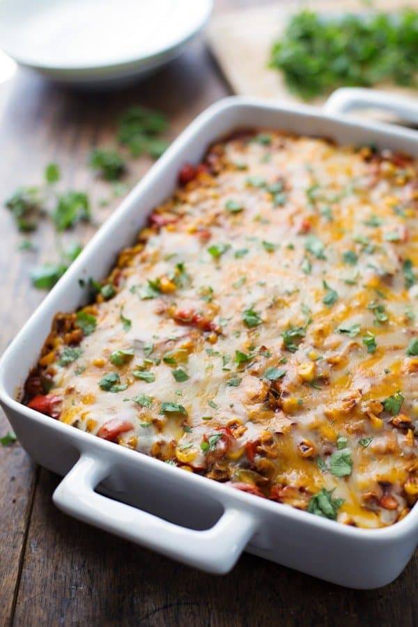 Mexican casserole in a white pan with cilantro in the background.