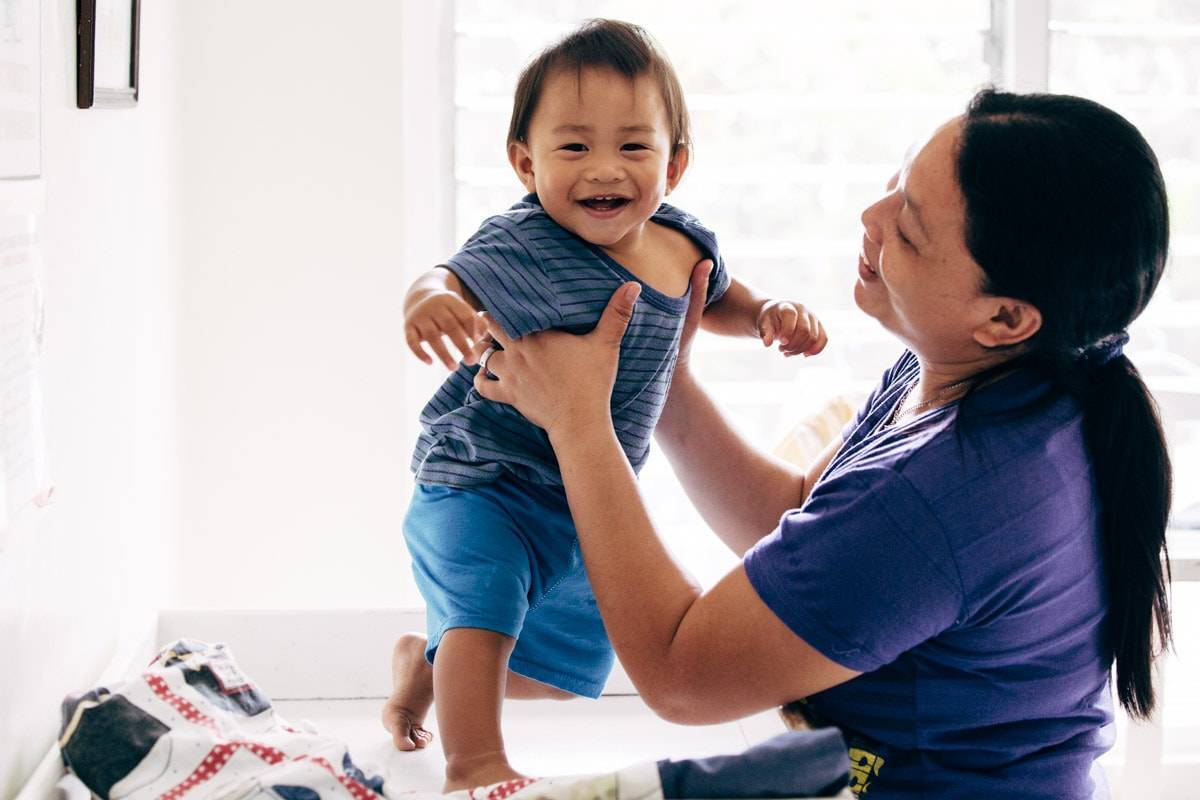 Woman holding a child smiling at camera.