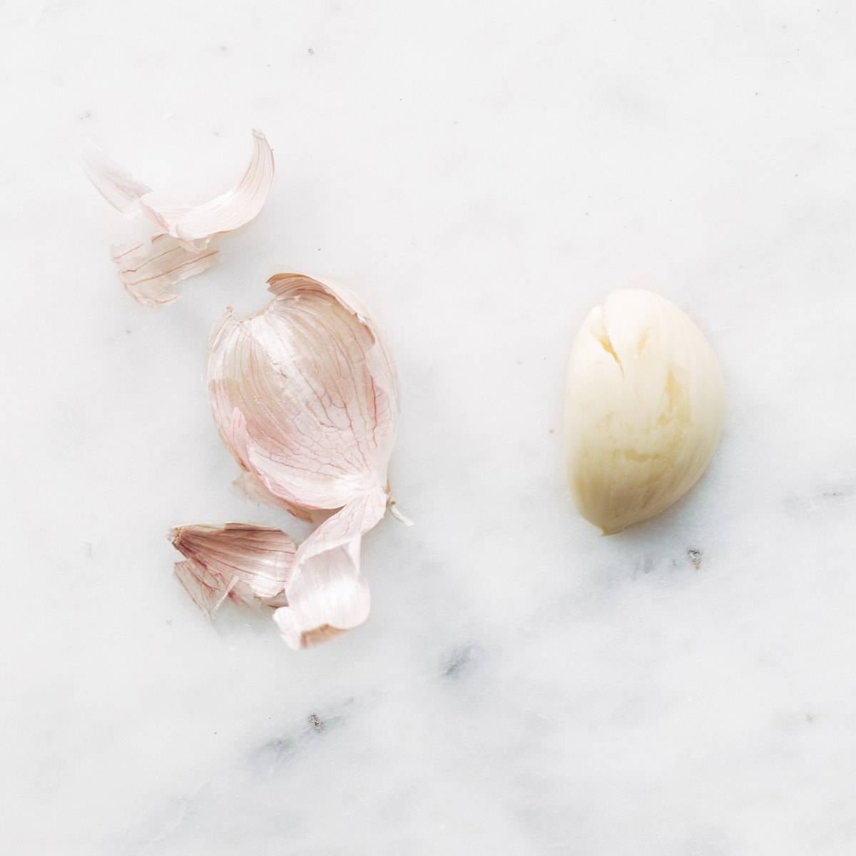 Garlic sitting on a white marbled surface.