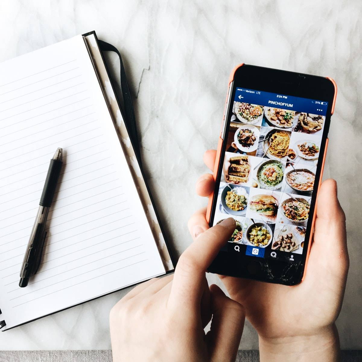 cracked iphone with hand and notebook with pen