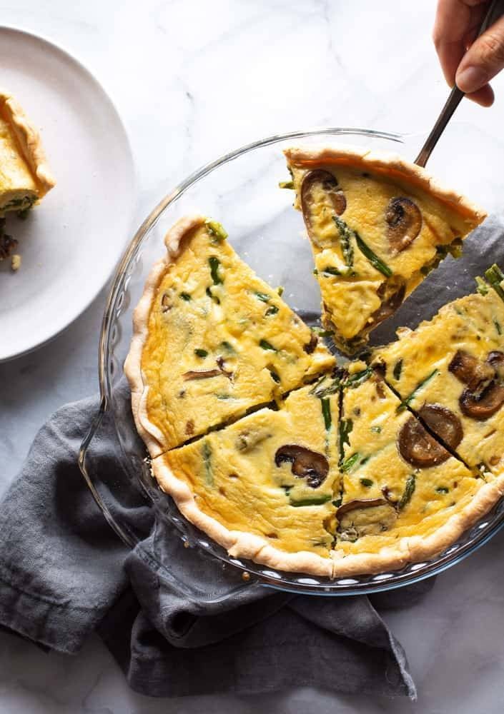 Picking up slice of quiche from pan.