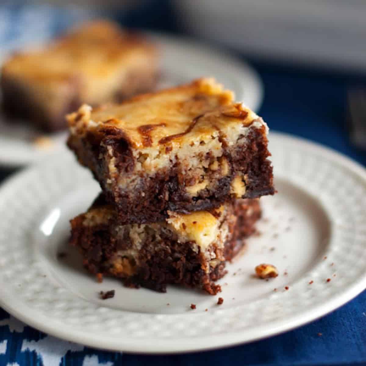 Two white chocolate cheesecake brownies on a plate.